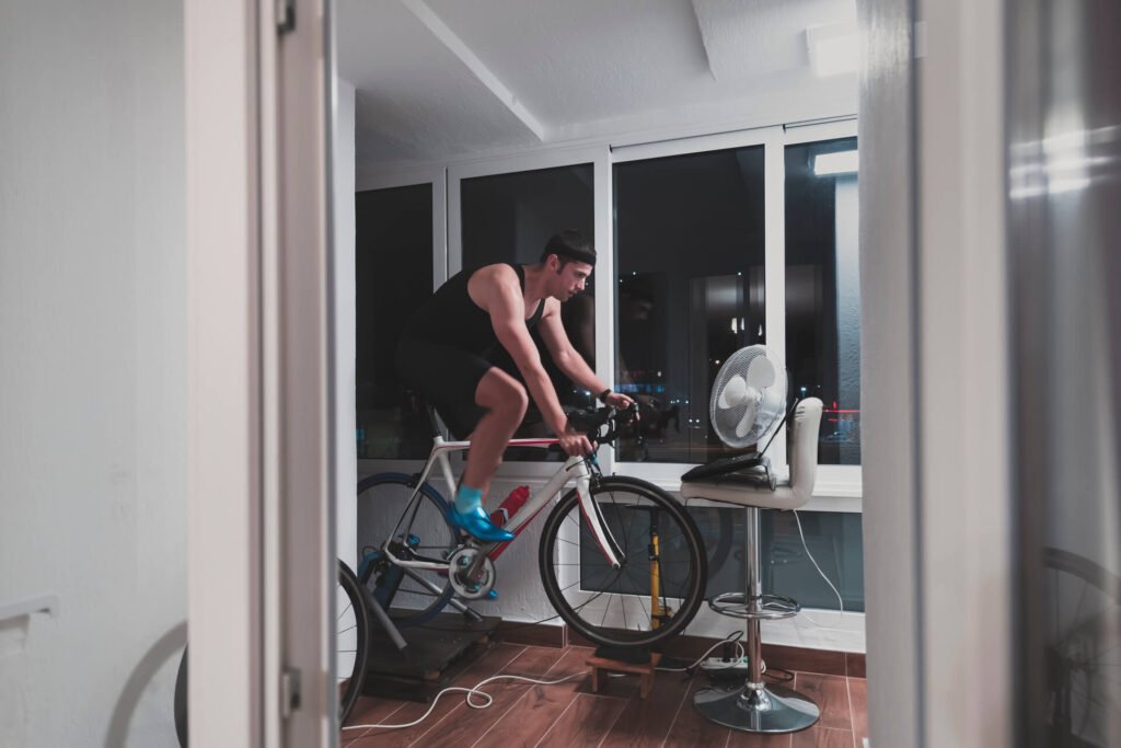 Man cycling on the machine trainer he is exercising in the home at night